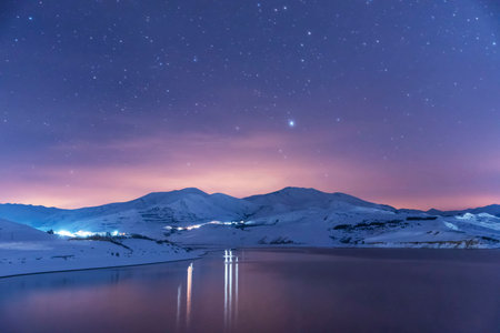 Beautiful winter landscape. Panoramic view on the lake and mountains peaks snow-covered at the starry night.の写真素材