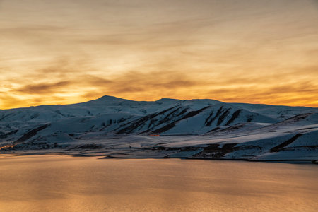 Beautiful winter landscape. Panoramic view on the lake and mountains peaks snow-covered on the sunset.の写真素材