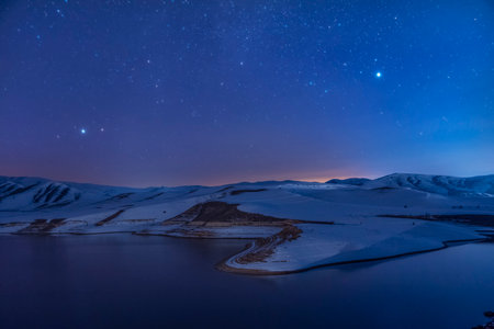 Beautiful winter landscape. Panoramic view on the lake and mountains peaks snow-covered at the starry night.の写真素材