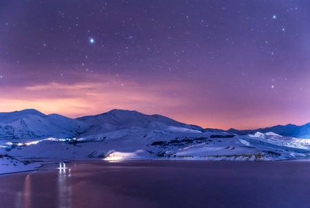 Beautiful winter landscape. Panoramic view on the lake and mountains peaks snow-covered at the starry night.の写真素材