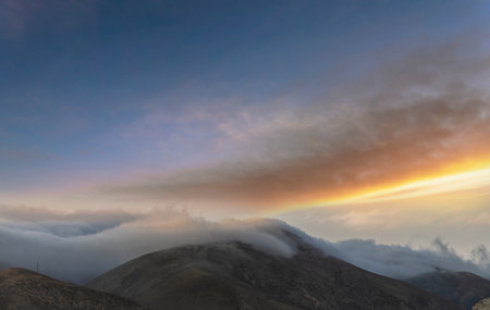 Sunset in the mountains with clouds and fog. Panorama.