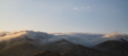 Panoramic view of the mountain range in the clouds at sunsetの写真素材