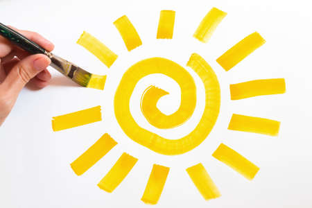 	Hand with paintbrush and picture of sunの写真素材