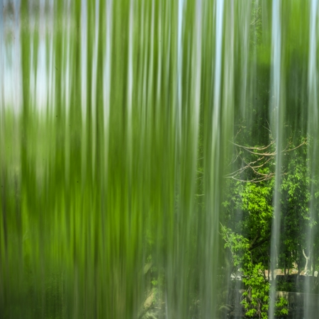 Behind a waterfal. A beautiful view of a blue sky and green trees through the falling water cascade.の写真素材