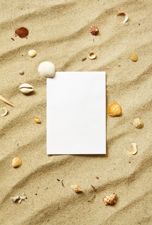 White card on sand with waves and sea shellsの写真素材