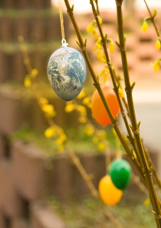 Easter egg as Earth globe hanging in a bush