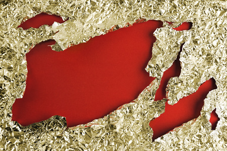 Background with a red uneven hole in metallic foil.の写真素材