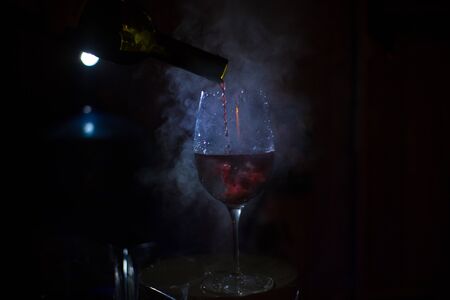 glass on a dark background, red wine is poured.の写真素材
