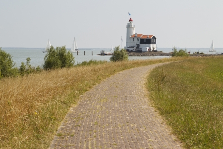 Landscape photo showing a dyke leading up to a beautiful old lighthouse の写真素材