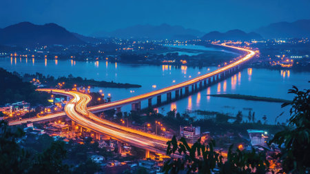 Stunning view of a picturesque Thai highway at night, showcasing a beautiful illuminated bridge over a river, creating a serene and vibrant atmosphere.の素材