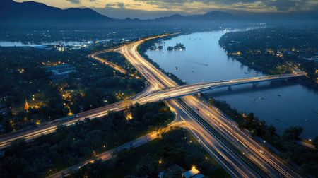 A stunning aerial view of a dynamic highway intersection at dusk. The bright lights create a vivid contrast against the tranquil landscape, highlighting urban life.の素材