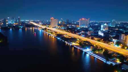 A stunning nighttime view of a highway intersection illuminated by vibrant lights, reflecting off the river, showcasing modern urban architecture and dynamic energy.の素材