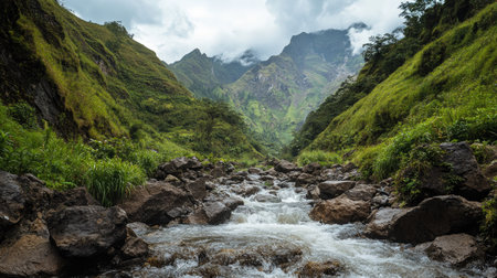 Mountain stream cascading down rocky terrain, surrounded by lush greenery and towering peaks.の素材
