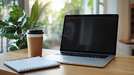 A clean and modern work desk with a laptop, notebook, and coffee cup. The large empty space on the desk surface offers ample room for text.の素材