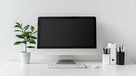 A minimalistic home office desk with a desktop computer, desk organizer, and a plant. The clear desk surface and wall offer ample space for copy.の素材