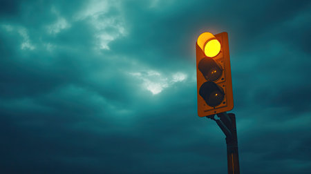 Traffic light at a small town intersection, with a cloudy sky and space for text above. The yellow light flickers, adding motion to the scene.の素材
