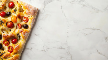 A delectable slice of focaccia bread crowned with cherry tomatoes and fresh herbs, set against a stylish marble background perfect for culinary presentations.の素材