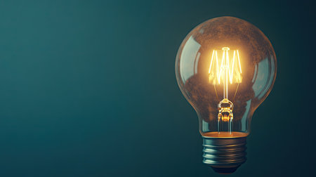 Side view of a light bulb illuminated, with a soft-focus background creating a clean space for text or product information on the right.の素材