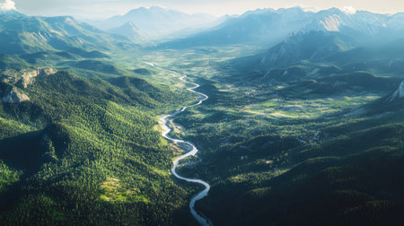 Top view of a mountain range with a winding river cutting through the valley below, surrounded by dense forests and open meadows.の素材