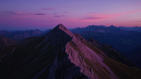 Top view of a mountain ridge at dusk, with the sky turning pink and purple, leaving ample room for copy space above the peaks.の素材