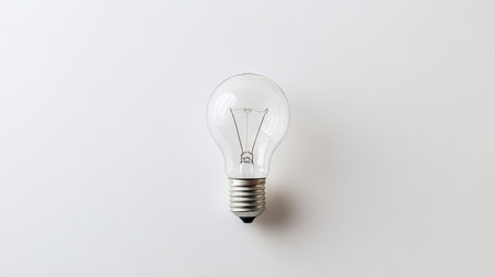 Flat lay of a light bulb with a clean, white surface, providing plenty of room for text or product placement on one side.の素材