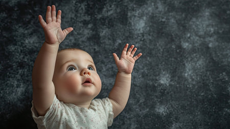 Baby reaching up with one hand toward the camera, with open space for text around.の素材