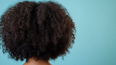Back view of a woman natural curls, with a large portion of the background left blank for copy placement.の素材