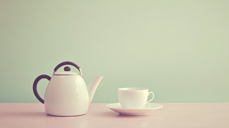 A kettle and teacup set on a table, with a neutral background offering a large area for text or copy.の素材