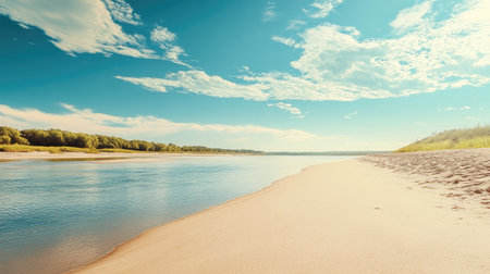 A sandy beach stretching along a gentle river, with a clean background of sky and water for text placement.の素材
