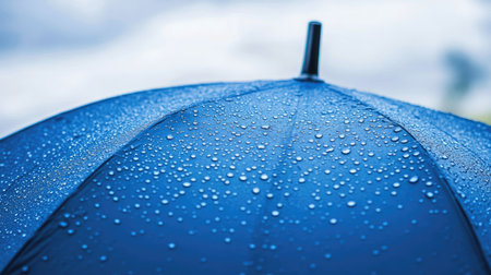 A stunning close-up view of raindrops resting on a blue umbrella, capturing the natural beauty of moisture in a serene, rainy atmosphere.の素材