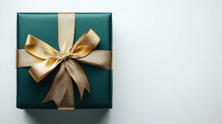 A beautifully wrapped green gift box tied with an elegant gold ribbon and finished with a perfect bow, isolated on white.の素材