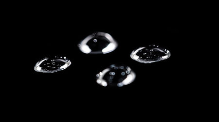 Close-up of clear water drops on a black background, showcasing the natural beauty and texture of water droplets, ideal for creative and artistic shotsの素材