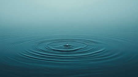 Rain falling on a blue water surface, causing circular ripples to spread, creating a relaxing and peaceful water scene ideal for photographyの素材