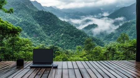 Laptop on a wooden deck, facing lush green mountains and misty clouds, creating a tranquil and inspiring workspace.の素材