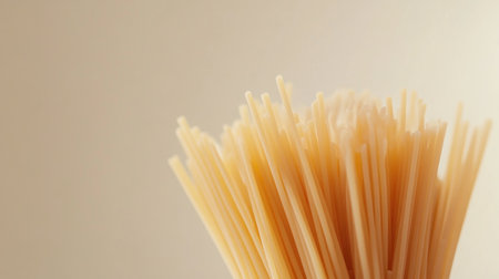 A delightful close-up of uncooked spaghetti showcasing its delicate texture against a soft beige background, perfect for culinary-themed projects or recipes.の素材