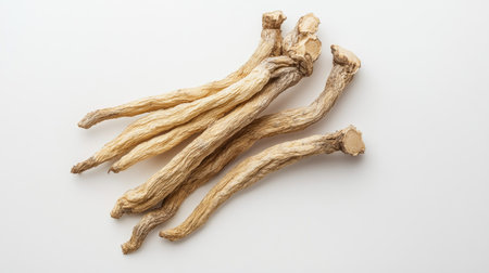 Minimalist top view of dried ginseng roots isolated on a white background. The organic texture and earthy colors are the focal point against the stark white surface.の素材