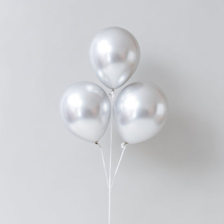 A collection of three elegant silver balloons gently floating against a soft white background, creating a minimalist and festive atmosphere suitable for various celebrations.の素材