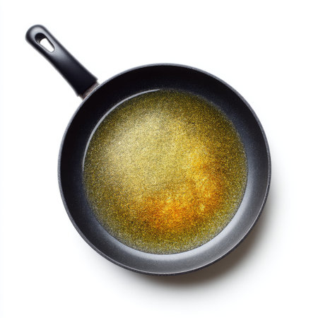 A close-up of golden oil surface reflecting light in a black frying pan, ideal for showcasing cooking, food preparation, and culinary creativity.の素材