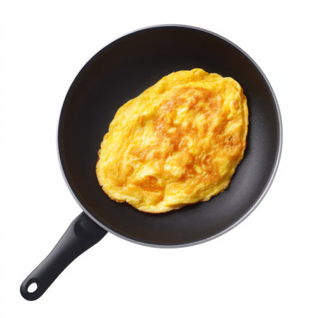 A golden egg omelette is beautifully cooked in a non-stick frying pan, showcasing its fluffy texture, ideal for a hearty breakfast or brunch meal.の素材