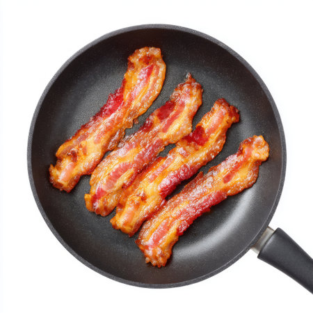 Delicious crispy bacon strips are cooking in a black frying pan, showcasing a mouthwatering breakfast option that enhances any meal experience.の素材