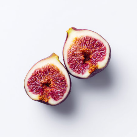 This image features two beautifully sliced fresh figs against a pure white background, highlighting their juicy texture and vibrant color. Ideal for food presentations or culinary inspirations.の素材