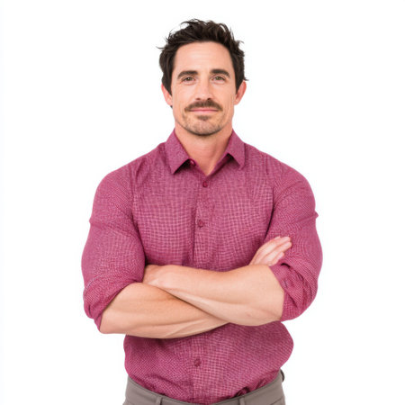 A confident man wearing a casual pink shirt stands with crossed arms, smiling directly at the camera, creating an approachable and professional look ideal for various uses.の素材