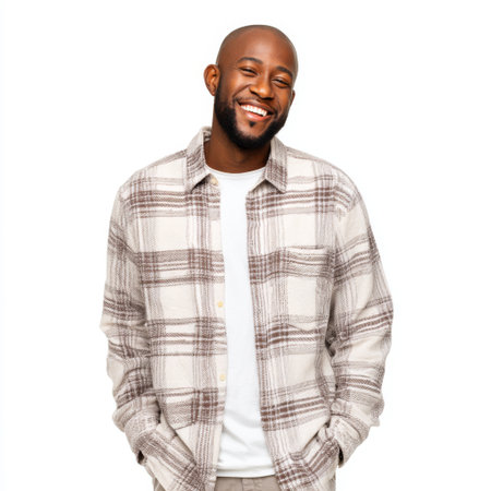 A cheerful young man wearing a plaid shirt and a simple white tee, radiating joy and confidence in a casual portrait setting. His warm smile invites connection.の素材
