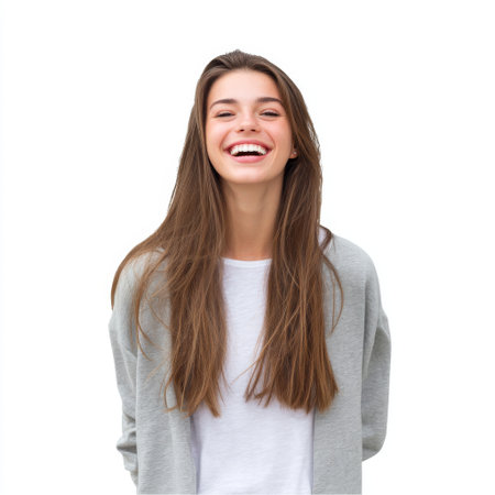 A joyful young woman with long brown hair smiles brightly, showcasing her cheerful personality in a casual outfit against a clean white backdrop.の素材