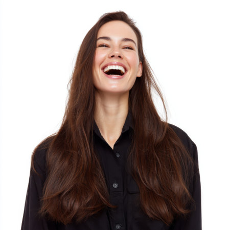 Radiating joy and confidence, this happy young woman laughs heartily against a clean white backdrop, showcasing her long hair and carefree spirit.の素材