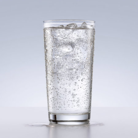 This image features a clear glass filled with crisp carbonated water and ice, showcasing refreshing bubbles against a soft gray backdrop.の素材