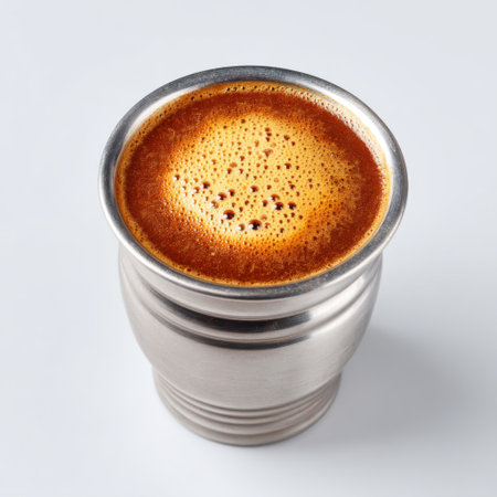 A top view of a stainless steel mug filled with hot brewed coffee featuring a creamy foamy layer. The image captures the inviting aroma and warmth of the drink, perfect for coffee lovers.の素材