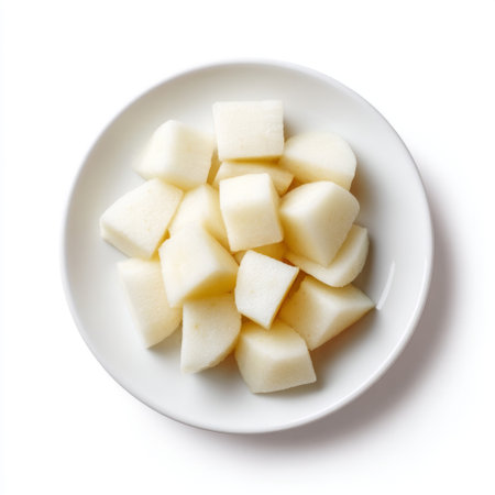 A minimalist arrangement of freshly cut white fruit cubes on a small plate, showcasing healthy eating and clean aesthetics with natural lighting.の素材