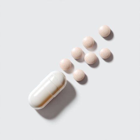 A white capsule lies next to soft chewable pills on a gray background, ideal for health-related themes, nutrition discussions, and wellness marketing.の素材