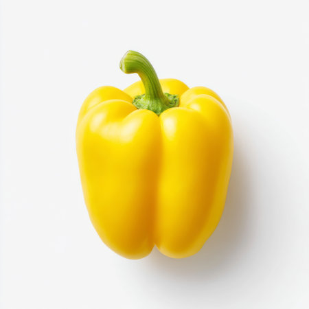 A vibrant yellow bell pepper sits isolated on a clean white background, symbolizing freshness and natural ingredients for healthy cooking and nutrition.の素材